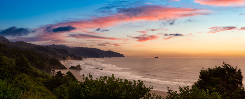 A gorgeous sunset over Ecola State Park with pink clouds and dark blue skies.