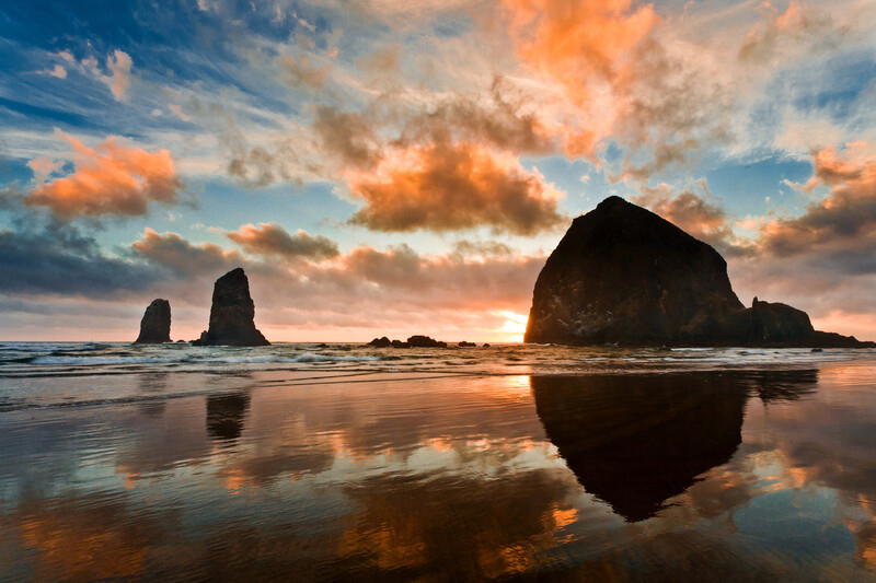 Cannon Beach Haystack Rock at sunset with beautiful blue sky and orange clouds.