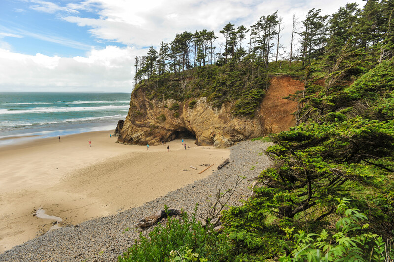 View of people on the beach, ocean, and cave at Hug Point, Oregon.