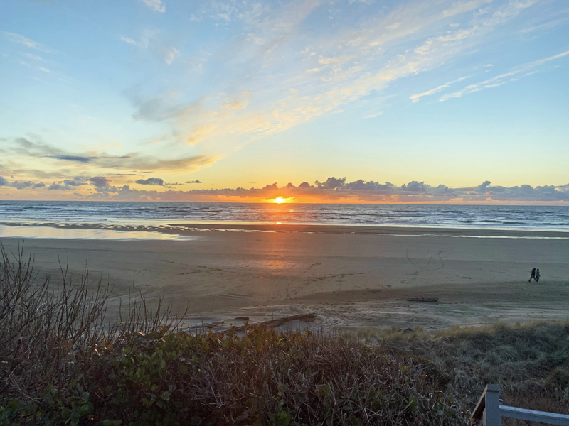 A couple walking on the beach during a beautiful Oregon Coast fall sunset.