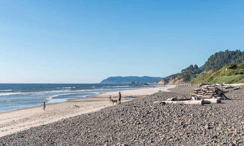 Clear blue skies, ocean, and people on the beach at Arch Cape, OR.