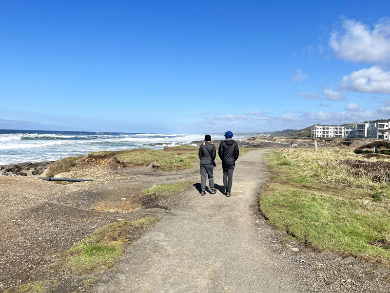 Couple walking along the rocky coastline of the Yachats 804 Trail