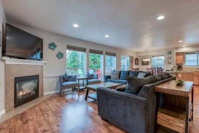 A cozy open living/dining/kitchen, gas fireplace, large screen TV, and floor to ceiling windows.