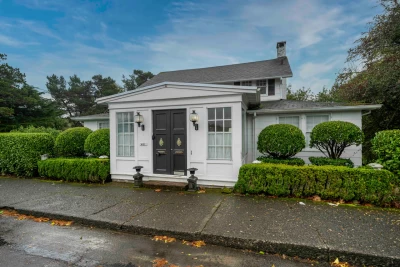 Elegant double door entrance and landscaping of white and black Gearhart vacation home.