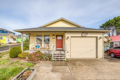 Tan 1-level house in a neighborhood with an orange front door (4 steps up) and a paved driveway with single car garage.