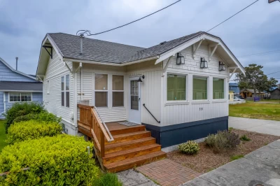 Cozy open living room, dining, and kitchen in remodeled historic cottage and sliders to the back deck.