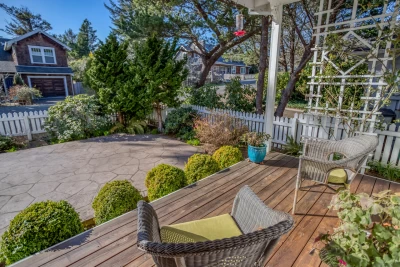 Front deck with wicker chairs, landscaped area, and white picket fence