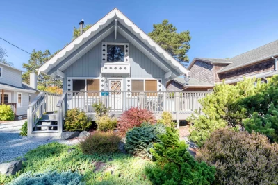 Cottage exterior with deck, parking, and street to the beach