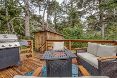 A back deck in a wooded area with cushioned outdoor furniture around a gas fire table.