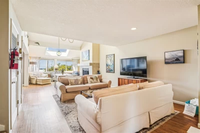 Beautiful open living room with skylights, windows, and dining by a wood fireplace.