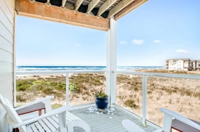 Oceanfront views from 2nd floor balcony with 2 white Adirondack chairs on a sunny day.