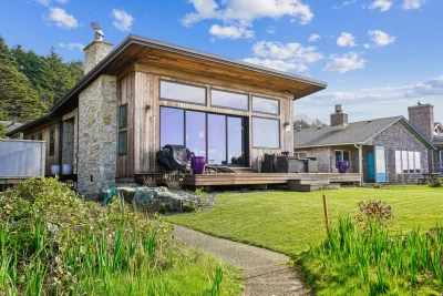 Stunning home, with vertical lap siding, large windows, deck with grill