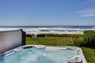 View of Pacific Ocean, grassy lawn, hot tub, driftwood and benches to sit and view ocean