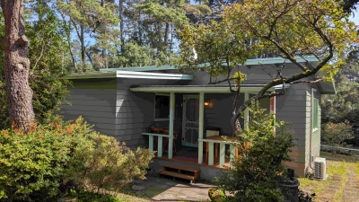 Vintage 1960s knotty pine cabin surrounded by evergreen trees in Florence Oregon wooded coastal setting